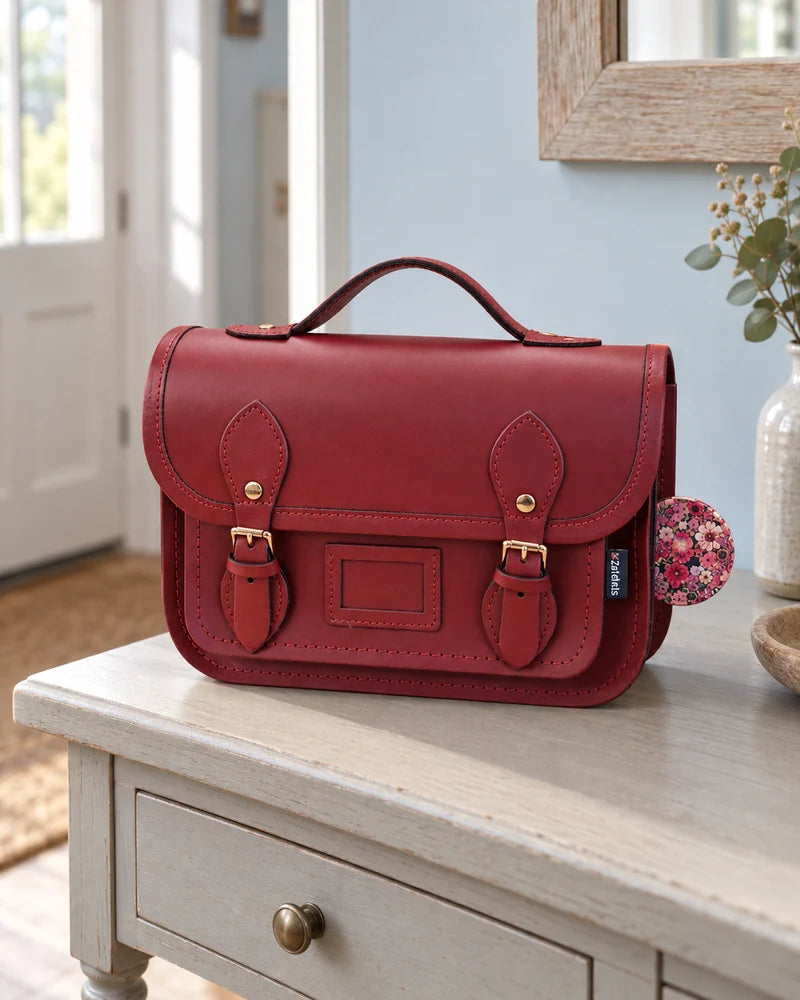 Oxblood satchel with a floral charm on a hallway table.