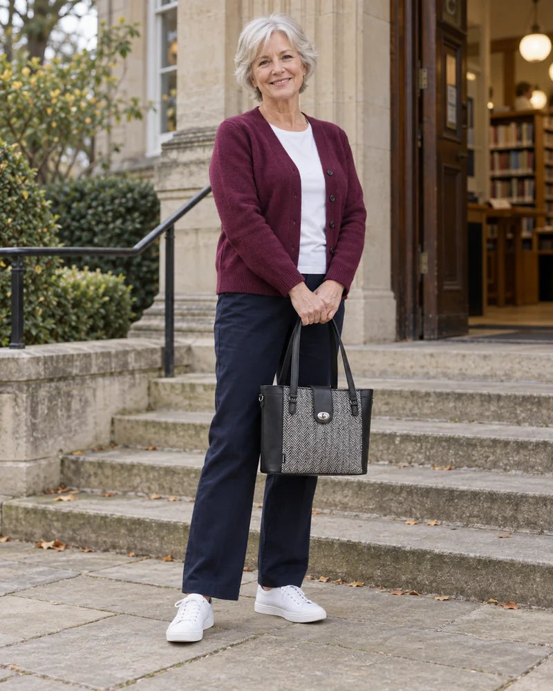 Woman holding a black and tweed shopper outside a library.