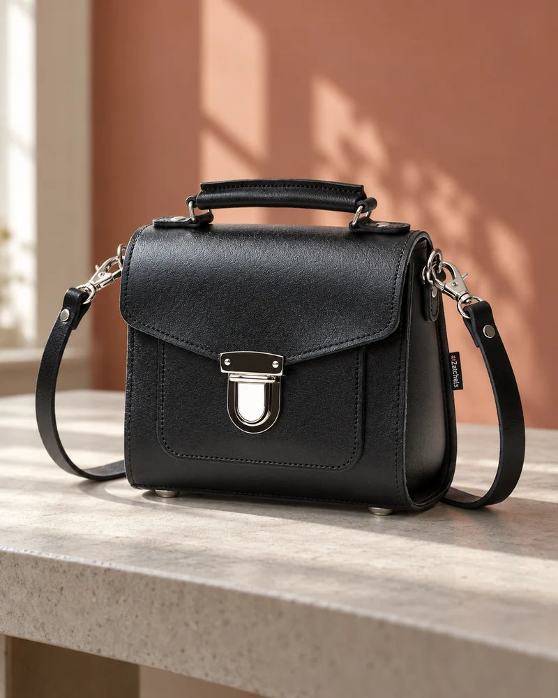 Small black handbag with a silver clasp on a console table.