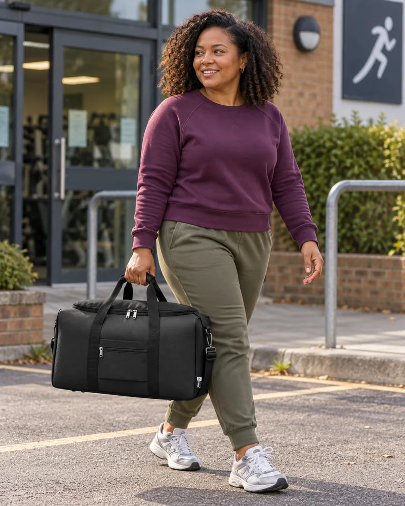 Woman carrying a black holdall outside a neighbourhood gym.