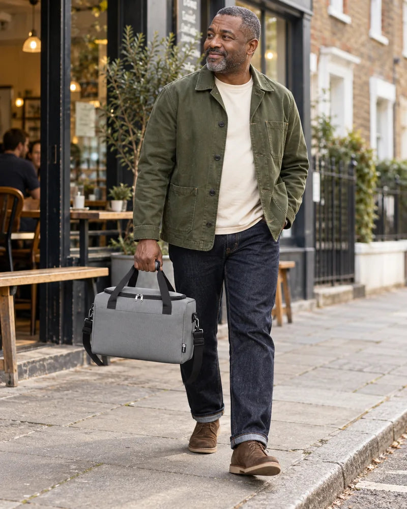 Person carrying a grey holdall on a city street.