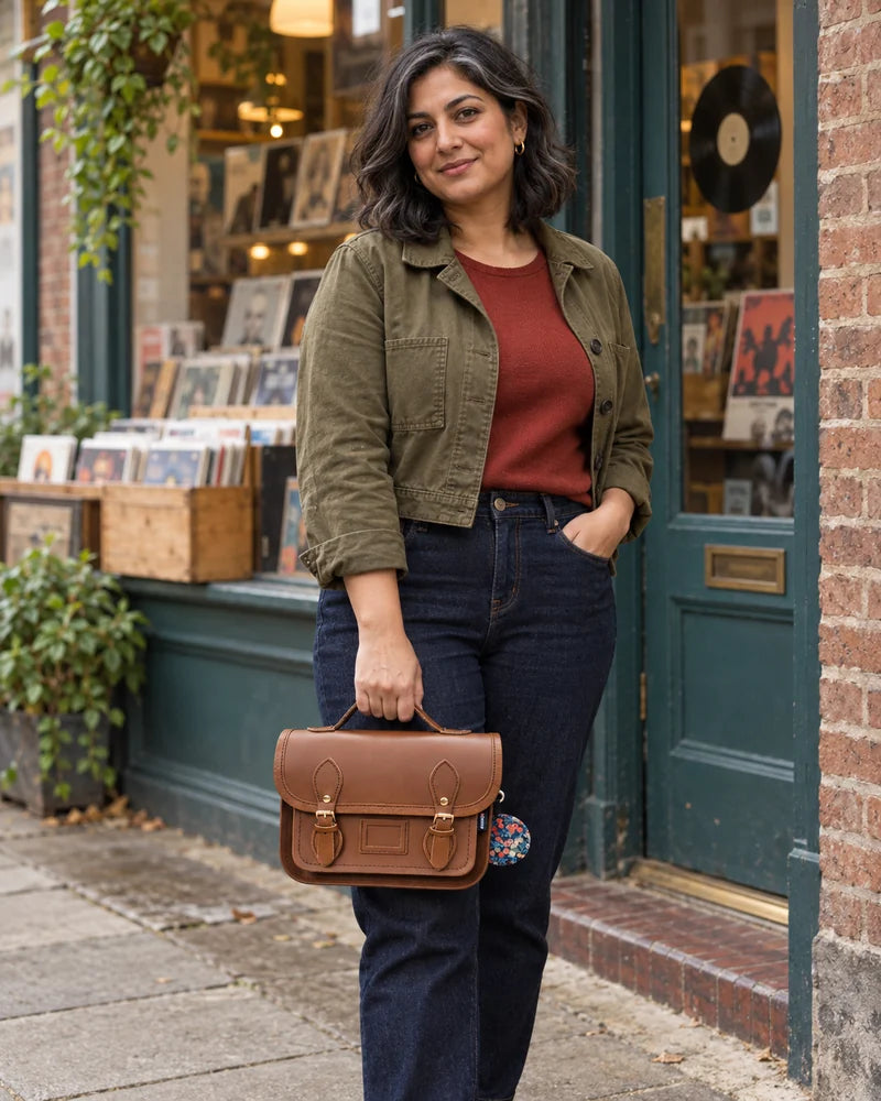 Woman holding a compact chestnut satchel outside a neighbourhood record shop